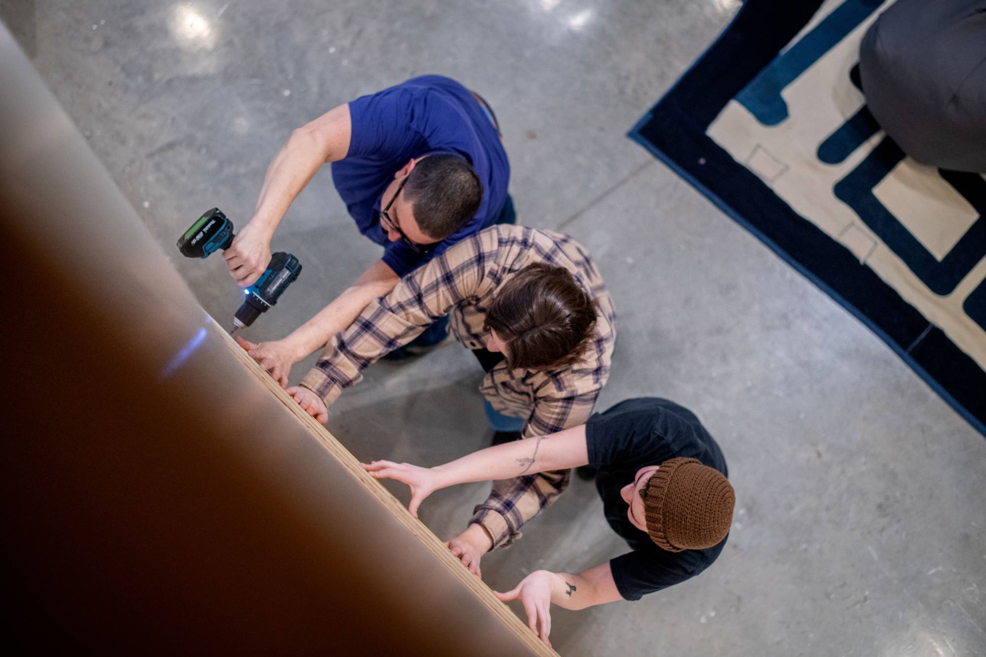 Students working to hang an image-based ceramic artwork with guest artist Emmy Bright.